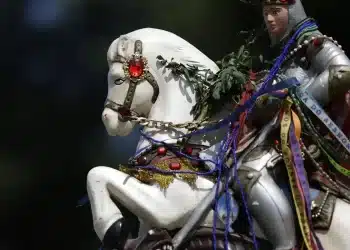 Estátua de São Jorge montado em cavalo, com fitas coloridas e adornos, representando a força e proteção do santo padroeiro.