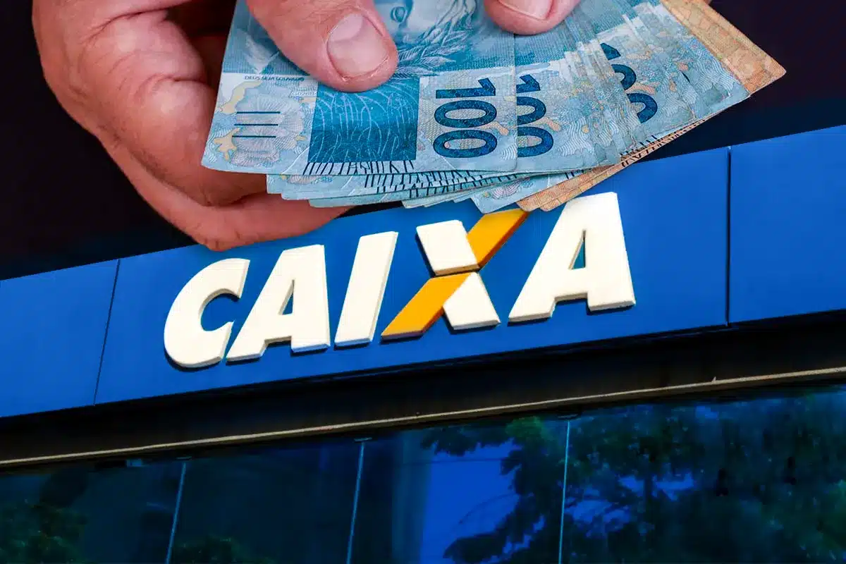 Mão segurando notas de cem reais em frente à fachada azul de uma agência da Caixa Econômica Federal, com letreiro em destaque, representando o pagamento do Auxílio Reconstrução de R$ 7.300 para famílias atingidas pelas chuvas em Minas Gerais.