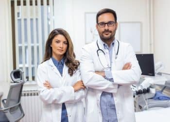 Dois médicos com jalecos em ambiente clínico representando a realidade da carreira médica e seus desafios profissionais.
