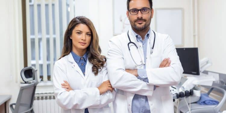 Dois médicos com jalecos em ambiente clínico representando a realidade da carreira médica e seus desafios profissionais.