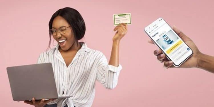 Jovem sorridente segura um Título de Eleitor enquanto utiliza um notebook, ao lado de uma mão exibindo um aplicativo de serviços eleitorais no celular.