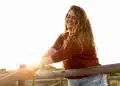 Mulher sorrindo ao ar livre durante um momento tranquilo de solitude e bem-estar emocional.