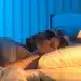 Casal dormindo com a luz acesa no quarto, ambiente com iluminação suave e azulada, refletindo os efeitos do sono com luz.