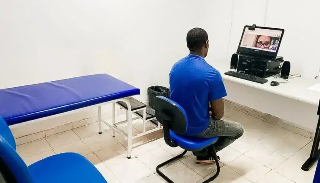 Homem em sala de atendimento do INSS durante a teleperícia, assistido por videoconferência.