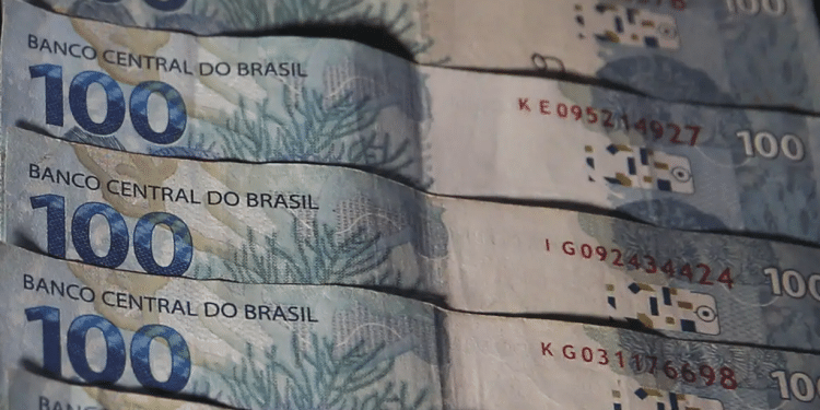 Notas de R$100 do Banco Central do Brasil sobrepostas em leque, exibindo tons azuis e verdes, simbolizando os pagamentos do 13º salário do INSS 2026.