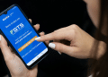 Trabalhadora acessa app oficial do FGTS da Caixa pelo celular.
