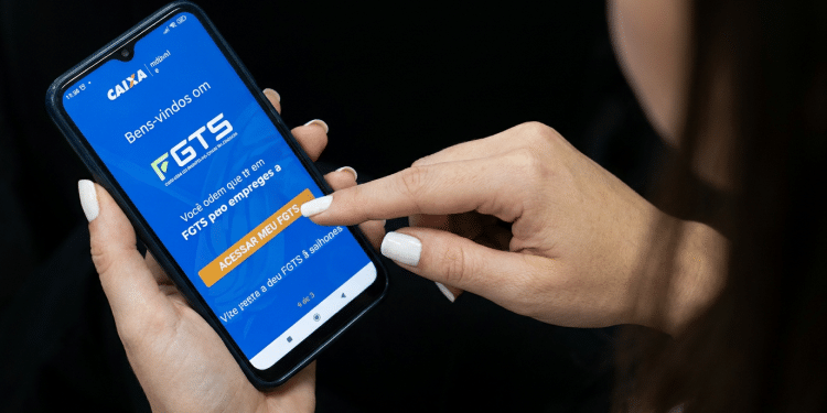 Trabalhadora acessa app oficial do FGTS da Caixa pelo celular.