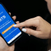 Trabalhadora acessa app oficial do FGTS da Caixa pelo celular.