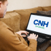 Homem olhando para a tela do notebook com o nome "CNH no Brasil".