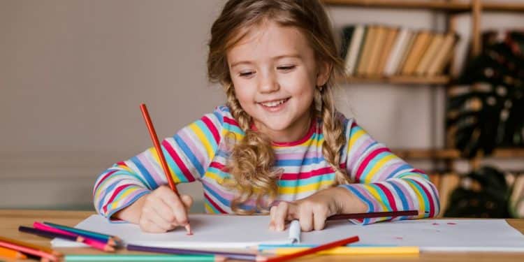 Criança loira desenhando.