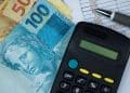 Cédulas de real brasileiro com calculadora e planilha financeira.