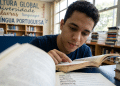 Jovem estuda língua portuguesa em biblioteca escolar.