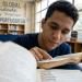 Jovem estuda língua portuguesa em biblioteca escolar.