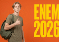 Jovem loiro com camiseta verde-oliva e mochila faz sinal de positivo ao lado do texto ENEM 2026 em fundo laranja.