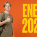Jovem loiro com camiseta verde-oliva e mochila faz sinal de positivo ao lado do texto ENEM 2026 em fundo laranja.