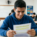 Estudante lê apostila de interpretação de texto em sala de aula.