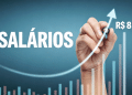 Mão desenhando seta em gráfico de barras coloridas sobre salários.