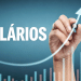 Mão desenhando seta em gráfico de barras coloridas sobre salários.