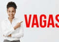 Profissional sorridente aponta para texto "VAGAS" em vermelho.