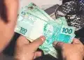 Pessoa segurando notas de 100 reais simbolizando possível aumento do BPC/INSS.