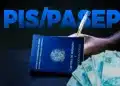 Carteira de Trabalho azul com cédulas de cem reais ao lado de cartão do PIS Pasep da Caixa sobre mesa de madeira