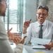Recrutador conversa com candidato sobre competências para vaga de emprego.