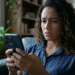 Mulher observa o celular com expressão preocupada, em referência à dúvida de ter sido bloqueada no WhatsApp.