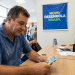 Homem conta cédulas de real diante de atendente em banco, sob banner do Novo Desenrola Brasil, durante renegociação de dívida