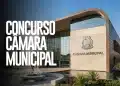 Prédio de Câmara Municipal com fachada de vidro, brasão no concreto, espelho d'água e praça com pessoa caminhando