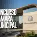 Prédio de Câmara Municipal com fachada de vidro, brasão no concreto, espelho d'água e praça com pessoa caminhando