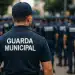 Agentes da Guarda Municipal em uniforme azul marinho durante formação, com destaque para guarda de costas usando boné