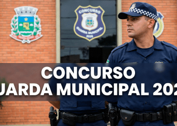 Guarda municipal fardado de boné xadrez azul em frente a prédio com brasões e emblema de concurso GCM 2026