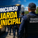 Guardas municipais uniformizados de azul enfileirados em formação com coletes identificados "Guarda Municipal"
