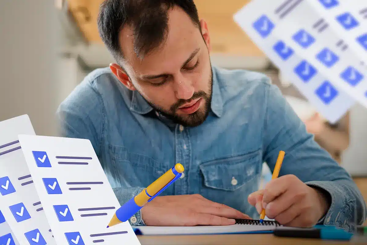 Homem estudando e escrevendo em caderno ao lado de folhas de checklist