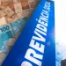 Depósitos do 13º do INSS em maio: cédulas de cinquenta e cem reais ao lado de placa azul da Previdência Social ilustram o pagamento antecipado a aposentados e pensionistas