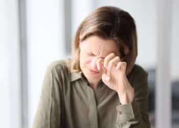 Mulher esfregando o olho após sentir desconforto