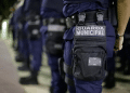 Agentes da Guarda Municipal uniformizados em formação com destaque para bolsa tática com identificação da corporação