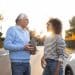 Homem mais velho e mulher jovem conversam de forma tranquila e sorridente ao lado de um carro, ilustrando os traços de personalidade de quem agradece no trânsito segundo especialistas