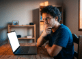 Homem observa a tela do notebook com expressão de dúvida