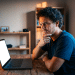 Homem observa a tela do notebook com expressão de dúvida