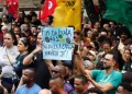 Manifestantes em ato público erguendo cartaz com a frase fim da escala 6x1 reduza a carga horária já.