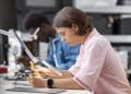 Formações para quem sai do ensino médio: jovem realiza atividade prática com instrumento de medição em laboratório, ao lado de colega trabalhando com microscópio