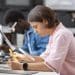 Formações para quem sai do ensino médio: jovem realiza atividade prática com instrumento de medição em laboratório, ao lado de colega trabalhando com microscópio