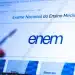Tela de computador exibindo portal oficial do ENEM com logotipo azul e mão segurando caneta apontando para seção Editais.