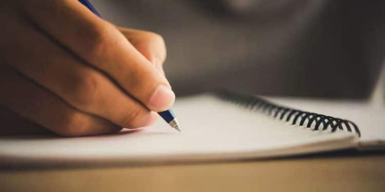 Pessoa escrevendo em caderno com caneta
