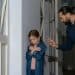 Homem adulto apontando dedo para menina ruiva de braços cruzados em postura defensiva, em corredor residencial, simbolizando o narcisismo parental.