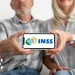 Casal de idosos segurando celular com logotipo do INSS em destaque na tela
