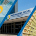 Composição visual com a fachada da sede da Previdência Social ao centro cercada por cédulas de cinquenta e cem reais