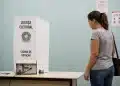 Eleitora diante de cabine de votação da Justiça Eleitoral em local de votação