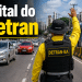 Agente do DETRAN-BA com colete amarelo e chapéu de fiscalização ergue a mão para orientar veículos em avenida de Salvador